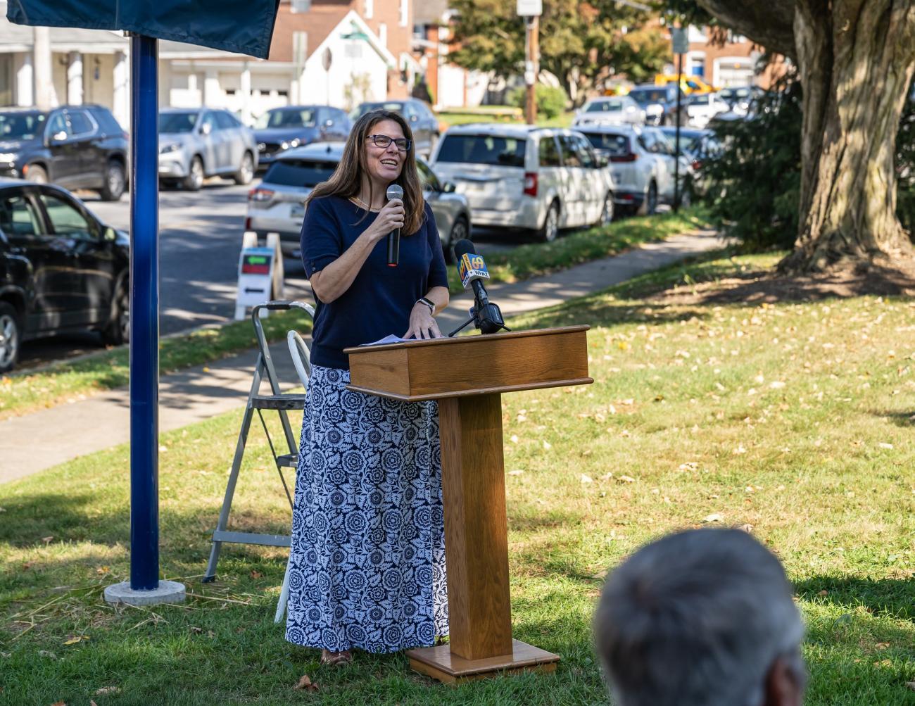 Mary Foltz speaks at a podium at Keith Haring marker unveiling event in October, 2024